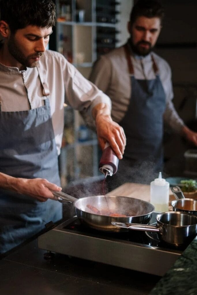 A chief is coooking in the kitchen ( what we do at hiremycooks)